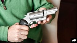 FILE - In this photo taken Feb. 26, 2016, Lance Toland, the owner of Lance Toland Associates, an aviation insurance company with three offices in Georgia, holds a Taurus revolver, in Atlanta.