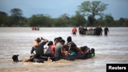 Flood-affected people cross a street on a boat in the aftermath of Hurricane Eta in La Lima, Honduras, Nov. 7, 2020.