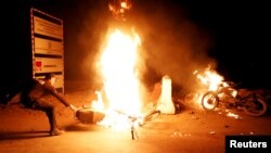 A policeman removes a bike set ablaze during a protest, after dispersing the supporters of the Tehreek-e-Labbaik Pakistan Islamist political party, in Karachi, Pakistan, Nov. 24, 2018.
