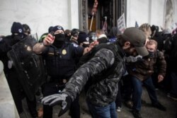 FILE - Members of law enforcement clash with pro-Trump protesters storming the U.S. Capitol, in Washington, Jan. 6, 2021.