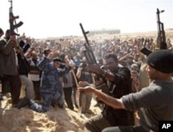 Libyan gunmen from the forces against Libyan leader Moammar Gadhafi fire in the air during a mass funeral for rebel gunmen killed in fighting in Ajdabiya, eastern Libya, March 3, 2011