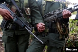 A couple from the 51st Front of the Revolutionary Armed Forces of Colombia (FARC) pose for the camera at a camp in Cordillera Oriental, Colombia, Aug. 16, 2016.