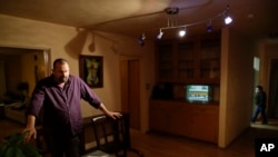 Mr. Lane, who did not give his first name, stands over a pile of documents on the dining room table in their home, Feb. 22, 2017, in San Diego. The Lane family has been on edge since President Donald Trump took office. The mother, a Mexican who is in the country illegally, now carries her birth and marriage certificates and other documents wherever she goes.