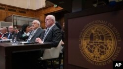 Riyad Al-Maliki, minister of Foreign Affairs of the Palestinian National Authority, right, and Riyad Mansour, Palestinian National Authority representative at the U.N., second right, wait for the U.N. highest court to open hearings in The Hague, Netherlands, Feb. 19, 2024. 