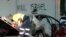 This frame grab from video provided by the Australian Broadcast Corporation Dec. 11, 2024, shows a police officer walking past a torched car being removed from in front of anti-Israel graffiti on a wall in a Sydney suburb (image partially blurred by VOA).