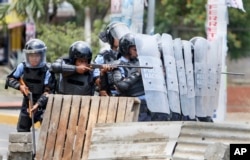 A Nicaraguan police officer aims his weapon at protesting students during a third day of violent clashes in Managua, Nicaragua, April 20, 2018.