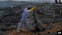 A Sri Lankan navy soldier hauls debris washed ashore from the burning Singaporean ship MV X-Press Pearl, which is anchored off Colombo port at Kapungoda, near Colombo, Sri Lanka, May 27, 2021.