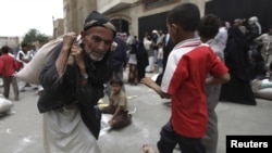A man carries food aid provided by the Red Crescent Society in Sanaa July 2, 2012.