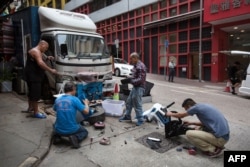 A man watches as people salvage usable materials from discarded office furniture for their secondhand shop in Hong Kong, Dec. 22, 2018.