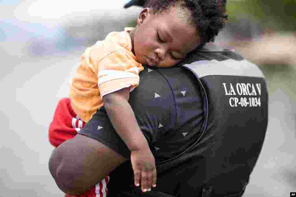 Un migrante haitiano sostiene a su hijo antes de abordar un bote hacia Capurganá.