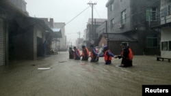 Rescue workers walk on a flooded street at a town hit by Typhoon Soudelor in Ningde, Fujian province, China, Aug. 9, 2015. 
