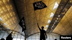 Anti-extradition bill protesters wave flags with Chinese calligraphy that reads "Liberate Hong Kong, the revolution of our times," at a mass demonstration at Hong Kong International Airport, in Hong Kong, China, Aug. 12, 2019.