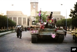 FILE - Tanks manned by Taliban fighters and decorated with flowers are shown in front of the the presidential palace in Kabul, Sept. 27, 1996. The Islamic rebels executed President Najibullah the day before.