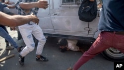 Kashmiri protesters gather around an Indian paramilitary vehicle as it runs over a man during a protest in Srinagar, Indian controlled Kashmir, June 1, 2018. 