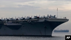 FILE - Sailors and fighter jets are seen on the deck of the U.S. aircraft carrier USS Ronald Reagan as it anchors off Manila Bay for a goodwill visit, June 26, 2018, west of Manila, Philippines.