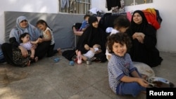 FILE - Wives of former Islamic State fighters sit with their children at a camp for displaced people in Ain Issa, north of Raqqa, Syria, June 21, 2017.