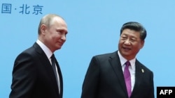 FILE - China's President Xi Jinping, right, and Russia's President Vladimir Putin smile during the welcoming ceremony on the final day of the Belt and Road Forum in Beijing, April 27, 2019.