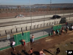Central American migrants bathe at a temporary shelter, near barriers that separate Mexico and the United States, at a temporary shelter in Tijuana, Mexico, Nov. 17, 2018.