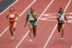 FILE - Blessing Okagbare of Nigeria, center, competes in round 1 of the Women's 100m at the Tokyo Olympics at Olympic Stadium, Tokyo, Japan, July 30, 2021.