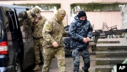 Un marinero ucraniano (derecha) es escoltado por un agente de inteligencia ruso a una corte en Simferool, Crimea, el martes 27 de noviembre de 2018.