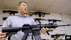 FILE - John Jackson, co-owner of Capitol City Arms Supply, shows off an AR-15 assault rifle for sale, Jan. 16, 2013, at his business in Springfield, Illinois.