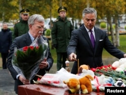 U.S. national security adviser John Bolton, left, and U.S. Ambassador to Russia Jon Huntsman attend a flower-laying ceremony at a World War II monument in Moscow to commemorate victims of a recent attack on a local college, Oct. 23, 2018.