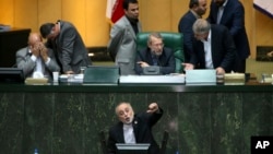 FILE - Head of Iran's Atomic Energy Organization Ali Akbar Salehi, bottom, speaks in an open session of parliament while discussing a bill on Iran's nuclear deal with world powers, in Tehran, Iran, Oct. 11, 2015.