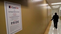 FILE - A guard passes a sign for CoreCivic at the Otay Mesa Detention Center, Aug. 23, 2017, in San Diego. The facility was at the center of the first big novel coronavirus outbreak at a U.S. immigration detention center in April 2020.