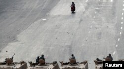Two men on a scooter ride near soldiers on military vehicles at Abbasiya square near Egypt's Defence Ministry, in Cairo, May 4, 2012. 