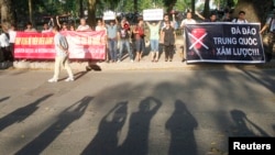A plainclothes policeman walks past demonstrators during an anti-China protest in front of the Chinese embassy in Hanoi, May 13, 2014.