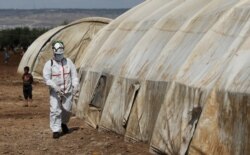 Anggota Pertahanan Sipil Suriah menyemprotkan cairan disinfektan di tenda di kamp Bab Al-Nour untuk mencegah penyebaran virus corona (COVID-19) di Azaz, Suriah, 26 Maret 2020. (Foto: Reuters)