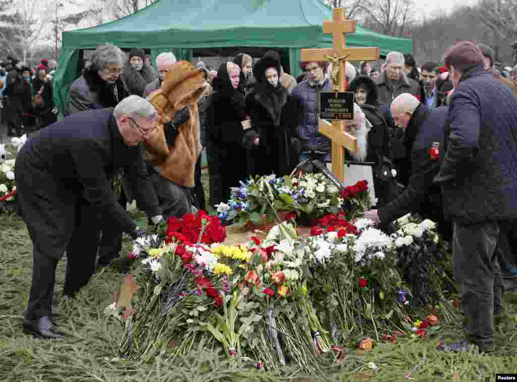 Mourners, including Mikhail Kasyanov (left), an opposition leader and former Russian prime minister, lay flowers at the grave of Russian leading opposition figure Boris Nemtsov during his funeral in Moscow, March 3, 2015.