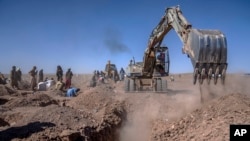 Afghans dig a trench for a common grave for their relatives killed in an earthquake to a burial site in Zenda Jan district in Herat province, western of Afghanistan, Oct. 9, 2023. 