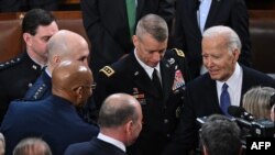 US President Joe Biden (R) shakes hands with Chairman of the Joint Chiefs of Staff General Charles Q. Brown Jr. as Biden departs at the conclusion of his State of the Union address in the House Chamber of the US Capitol in Washington, DC, on March 7, 2024
