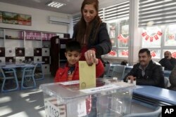 Arda Ozdemir, 7, casts his mother Kader Ozdemir's vote at a polling station at a primary school in Ankara, Nov. 1, 2015.