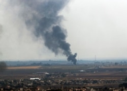 FILE - In this photo taken from the Turkish side of the Turkey-Syria border, in Ceylanpinar, Sanliurfa province, smoke billows from a fire in Ras al-Ayn, Syria, Oct. 20, 2019, days after the declaration of a cease-fire.
