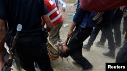 Nhan viên an ninh khiêng xác một nghi can chủ chiến bị bắn chết trong một cuộc chạm súng ở ngoại ô thành phố Lahore