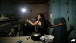 Archivo - Dugleidi Salcedo se queja a un vecino sobre el alto precio de los alimentos mientras prepara arepas para sus tres hijos en Caracas, Venezuela, el 14 de febrero de 2019.
