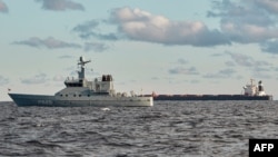 The Chinese bulk carrier Yi Peng 3, right, is anchored and being monitored by a Danish naval patrol vessel in the Kattegat strait, near the city of Granaa in Jutland, Denmark, on Nov. 20, 2024.