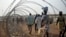 FILE - Displaced people walking next to a razor wire fence at the United Nations base in the capital Juba, South Sudan. 