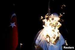 FILE - Supporters of Turkish President Tayyip Erdogan burn an effigy of U.S.-based cleric Fethullah Gulen hanged by a noose during a pro-government demonstration on Taksim Square in Istanbul, Turkey, July 18, 2016.