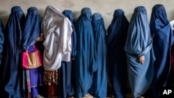 FILE - Afghan women wait to receive food rations distributed by a humanitarian aid group, in Kabul, Afghanistan, Tuesday, May 23, 2023. The Taliban have reportedly allowed female high school graduates to enroll in state-run medical institutes.