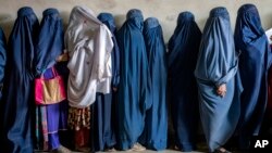 FILE — Afghan women wait to receive food in Kabul, Afghanistan, May 23, 2023. An independent assessment commissioned by the United Nations requires the Taliban to remove limits on women's rights to education and work.