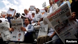 FILE - Press freedom activists read opposition newspaper Cumhuriyet during a demonstration in solidarity with the jailed members of the newspaper outside a courthouse, in Istanbul, Turkey, July 28, 2017. 