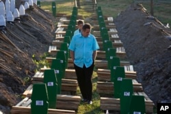 FILE - A Bosnian man walks among graves during a funeral ceremony for the 136 victims at the Potocari memorial complex near Srebrenica, 150 kilometers (94 miles) northeast of Sarajevo, Bosnia and Herzegovina, July 11, 2015.