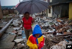 A boy amd a woman walk next to remains of houses destroyed by Hurricane Matthew in Baracoa, Cuba, Oct. 5, 2016.