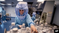 FILE - A laboratory worker simulates the workflow in a cleanroom of the BioNTech Corona vaccine production facility in Marburg, Germany, during a media day, March 27, 2021. 
