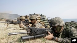 FILE – A South Korean Marine, right, and U.S. Marines aim their weapons near amphibious assault vehicles during the U.S.-South Korea joint landing military exercises as a part of the annual joint military exercise Foal Eagle between South Korea and the United States in Pohang, south of Seoul, South Korea, March 30, 2015. 