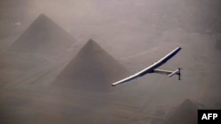FILE - This handout photo released by Solar Impulse 2 shows the solar-powered plane, piloted by André Borschberg, during the flyover of the pyramids of Giza prior to landing in Cairo, July 13, 2016. 