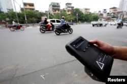 A man monitors air quality on a street in Hanoi, Vietnam, May 31, 2018.